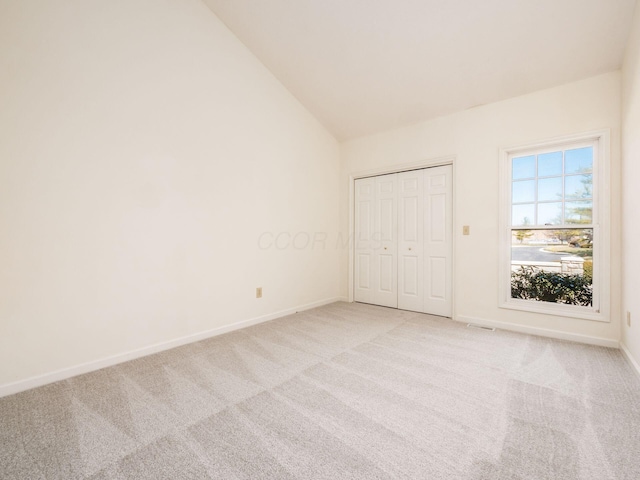 unfurnished bedroom featuring light colored carpet, baseboards, and lofted ceiling