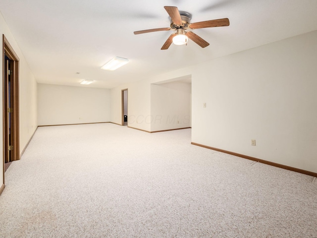 spare room with ceiling fan, baseboards, and light carpet