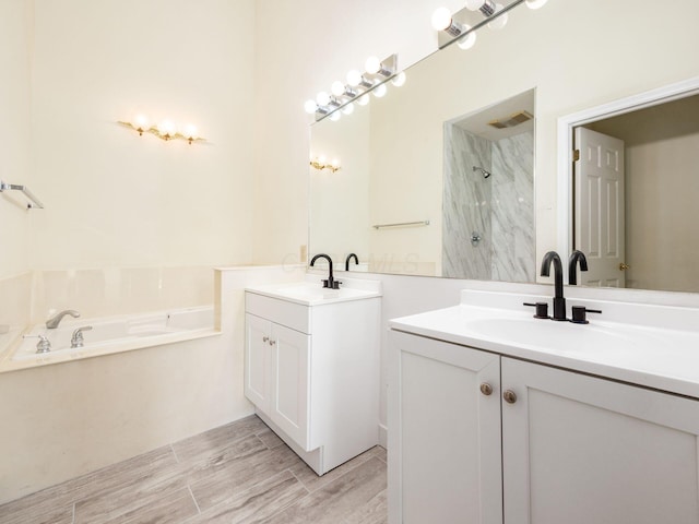 bathroom featuring visible vents, two vanities, walk in shower, and a sink