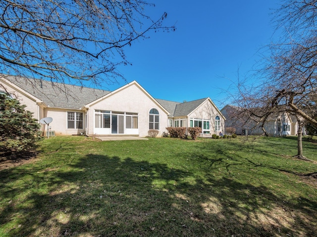 back of property featuring a lawn and stucco siding