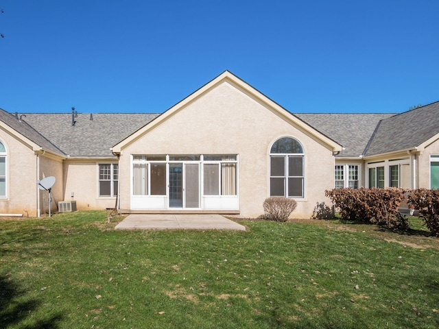 back of property featuring stucco siding, a yard, and roof with shingles