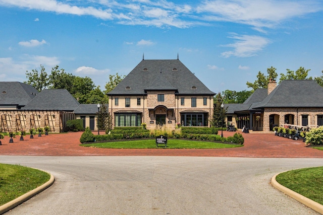 french provincial home with brick siding and curved driveway