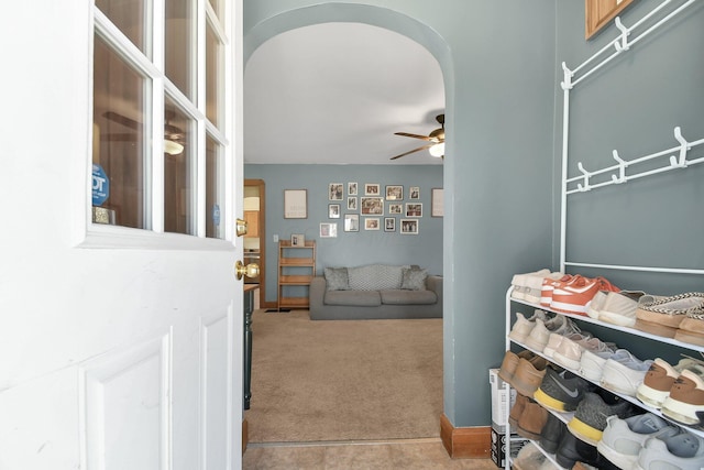 living area featuring a ceiling fan, arched walkways, and carpet floors