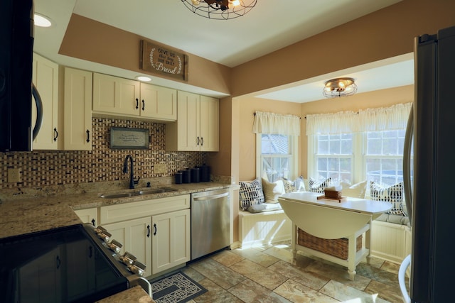 kitchen with stone tile floors, decorative backsplash, stainless steel appliances, and a sink