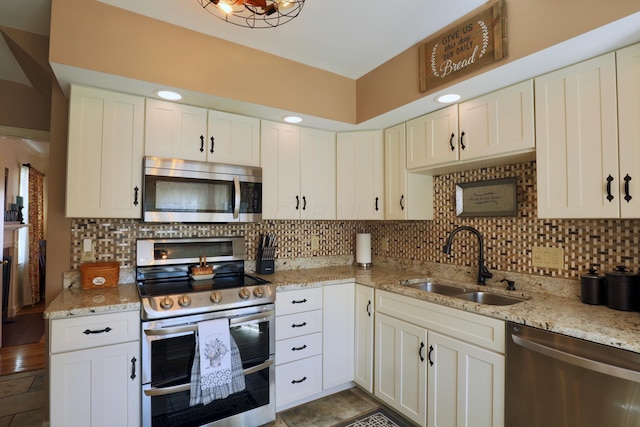 kitchen with a sink, decorative backsplash, light stone countertops, and stainless steel appliances