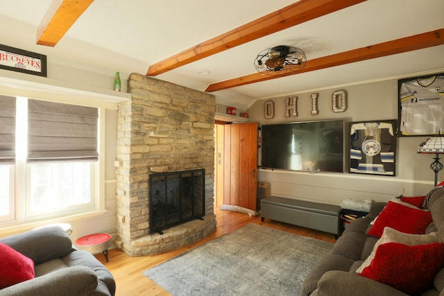 living room with beamed ceiling, wood finished floors, and a large fireplace