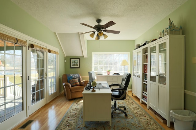 office with a ceiling fan, wood finished floors, visible vents, lofted ceiling, and a textured ceiling