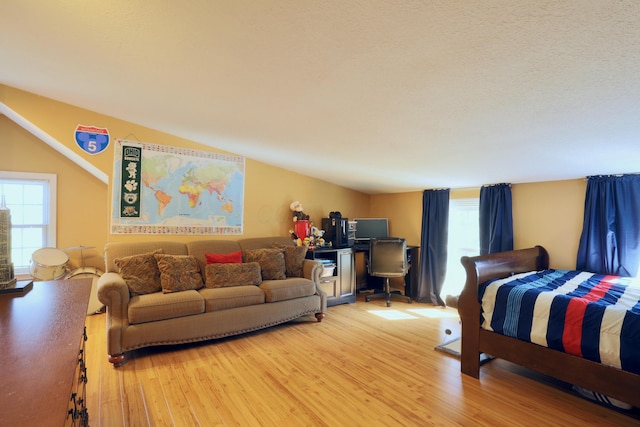 bedroom with light wood-type flooring and lofted ceiling