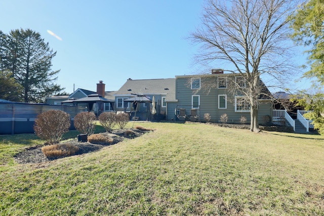 rear view of house featuring a gazebo, a lawn, and a chimney