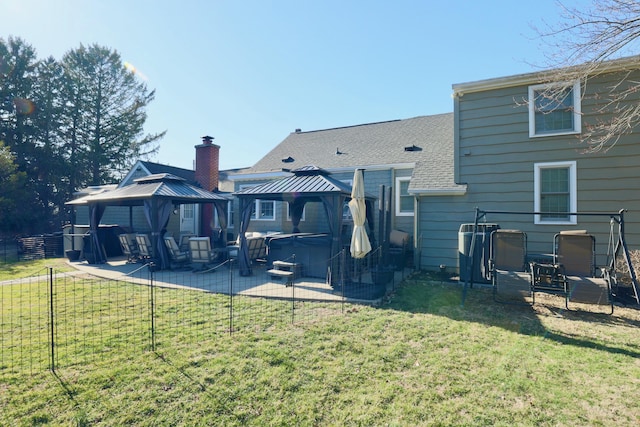 back of property with a gazebo, a patio area, a hot tub, and a lawn