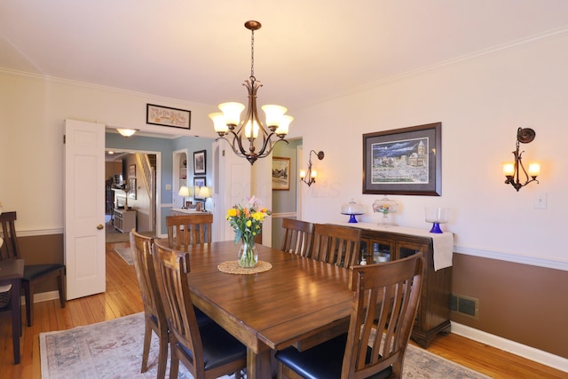 dining space with visible vents, baseboards, light wood-style floors, and crown molding