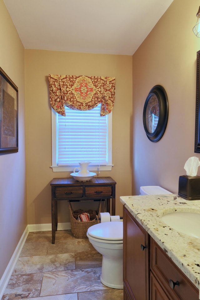 bathroom with baseboards, toilet, and vanity