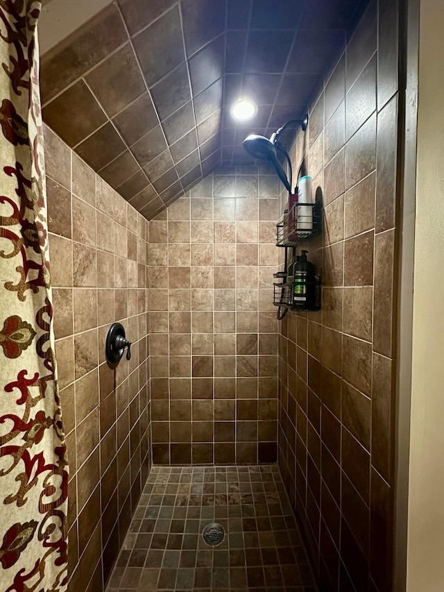 full bathroom with tiled shower and lofted ceiling