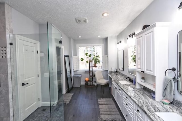 full bath with wood finished floors, double vanity, a freestanding tub, a sink, and a walk in shower