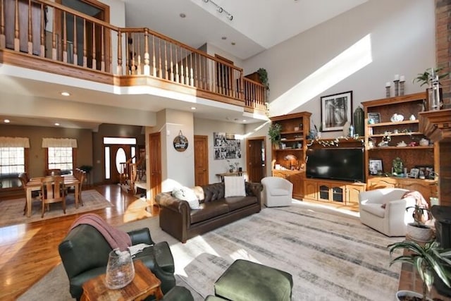 living area featuring track lighting, a high ceiling, recessed lighting, and wood finished floors