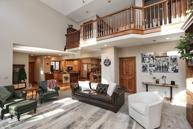 living area featuring a high ceiling, recessed lighting, and light colored carpet