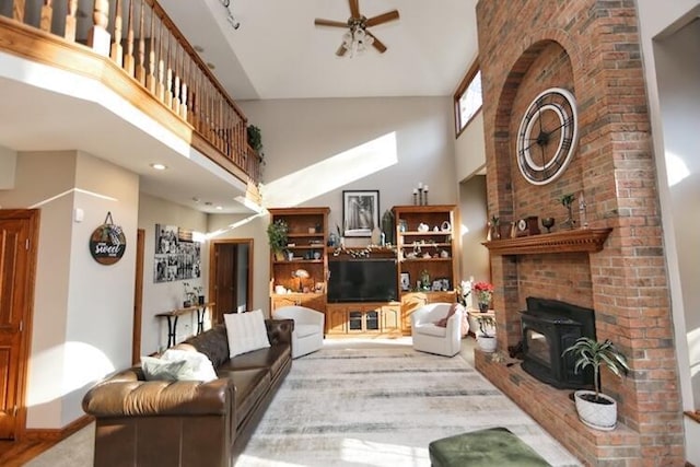 living area featuring a wood stove, a high ceiling, and a ceiling fan