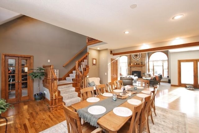 dining room featuring recessed lighting, light wood-type flooring, a fireplace, and stairs