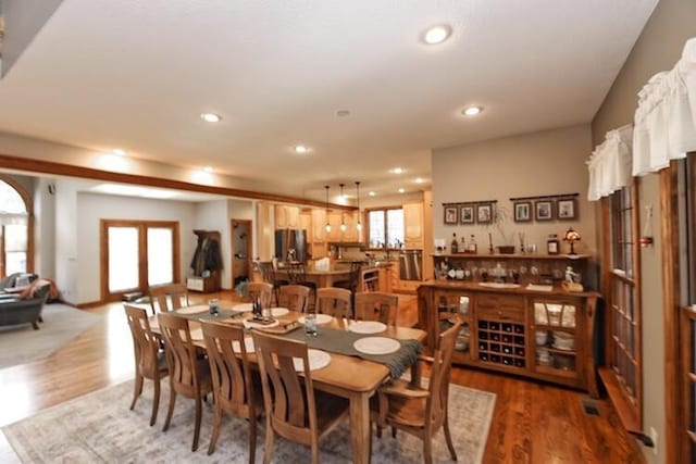 dining space with a wealth of natural light, french doors, and wood finished floors