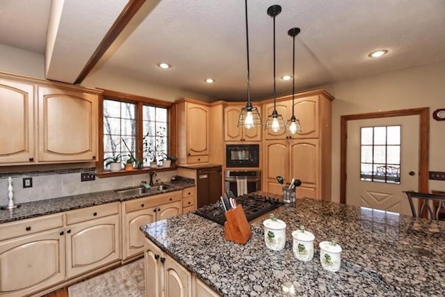 kitchen with a sink, dark stone counters, appliances with stainless steel finishes, and a wealth of natural light