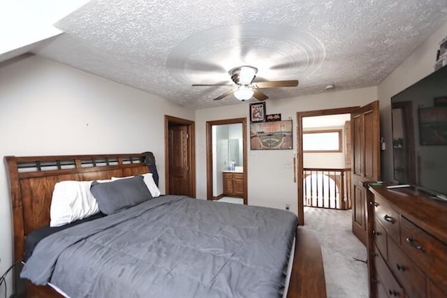 bedroom with a textured ceiling, ceiling fan, connected bathroom, and light carpet