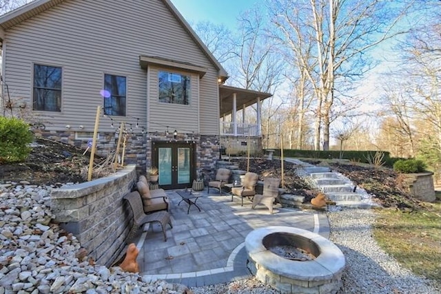 rear view of house with a patio, french doors, and a fire pit