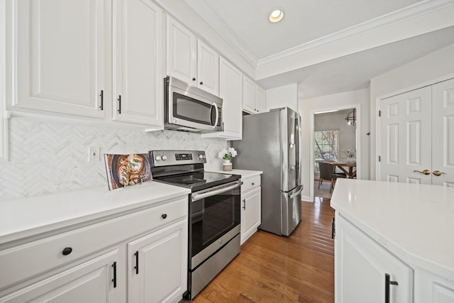 kitchen with decorative backsplash, stainless steel appliances, crown molding, and white cabinets