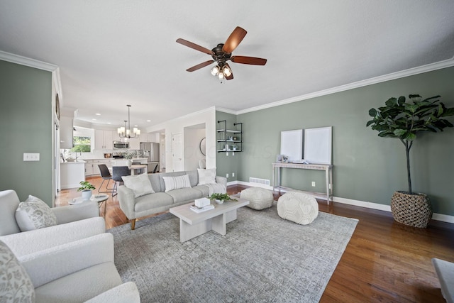 living room with visible vents, baseboards, ornamental molding, wood finished floors, and ceiling fan with notable chandelier