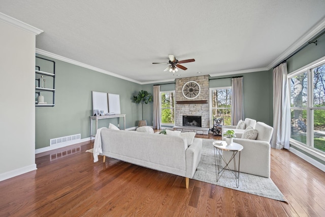 living room featuring ornamental molding, visible vents, ceiling fan, and wood finished floors