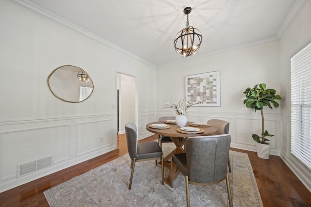 dining room featuring an inviting chandelier, visible vents, wood finished floors, and a decorative wall