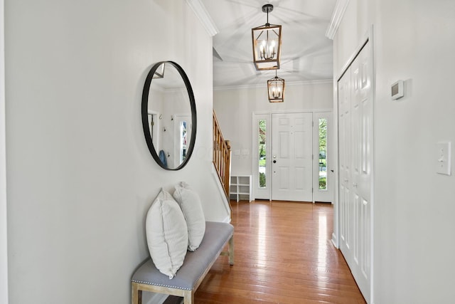 entrance foyer featuring a chandelier, stairway, wood-type flooring, and crown molding