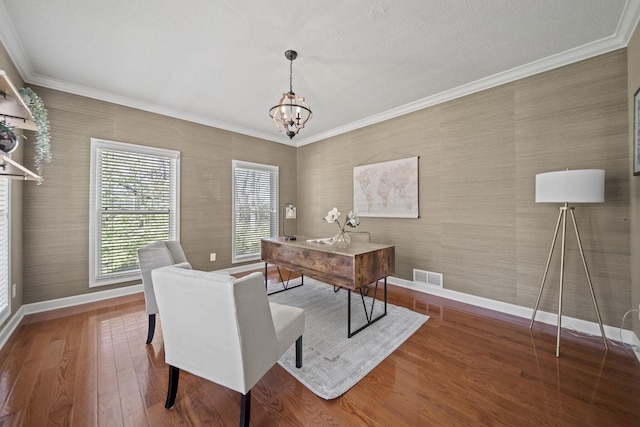 office featuring hardwood / wood-style flooring, crown molding, visible vents, a chandelier, and baseboards