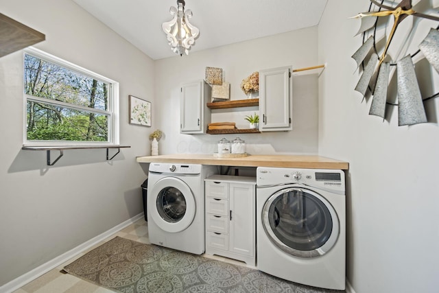 clothes washing area with a notable chandelier, washing machine and dryer, cabinet space, and baseboards