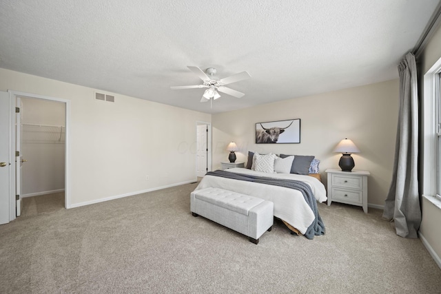 bedroom with carpet flooring, a ceiling fan, visible vents, baseboards, and a textured ceiling