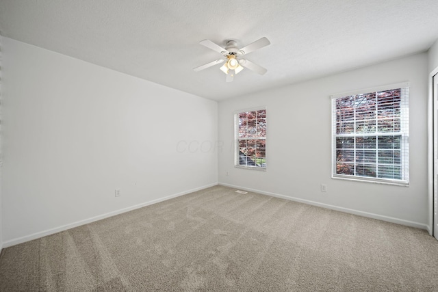 carpeted empty room with a ceiling fan and baseboards