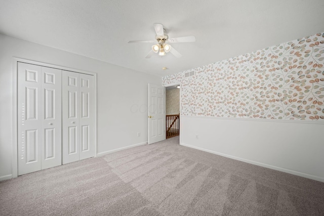unfurnished bedroom with visible vents, wallpapered walls, a closet, baseboards, and carpet