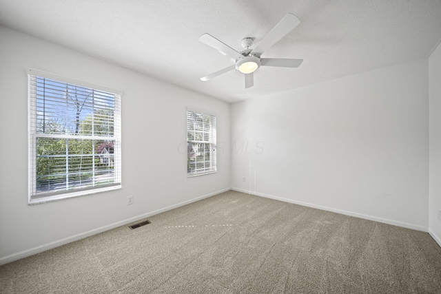 carpeted empty room with visible vents, ceiling fan, and baseboards
