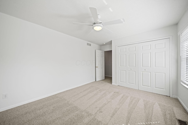 unfurnished bedroom with a closet, multiple windows, carpet flooring, baseboards, and visible vents