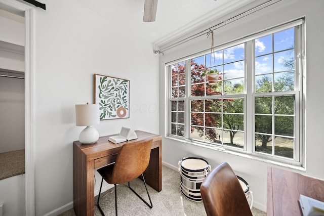 carpeted office space featuring baseboards and a ceiling fan