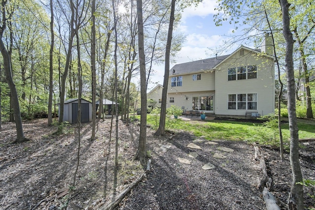 back of house featuring an outdoor structure, a storage unit, a chimney, a patio area, and a lawn