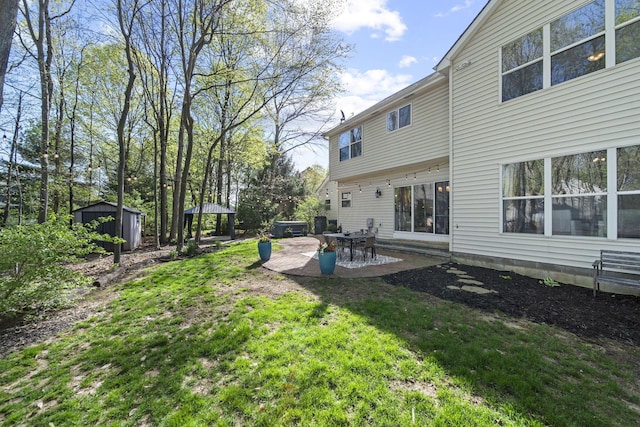 rear view of house with an outbuilding, a storage unit, a yard, and a patio area