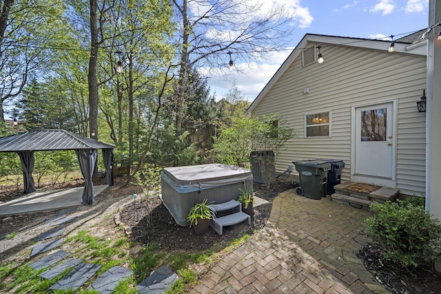 exterior space featuring entry steps, a gazebo, a patio area, and a hot tub