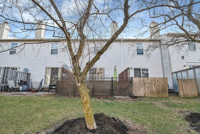 back of house with a yard, fence, and a chimney