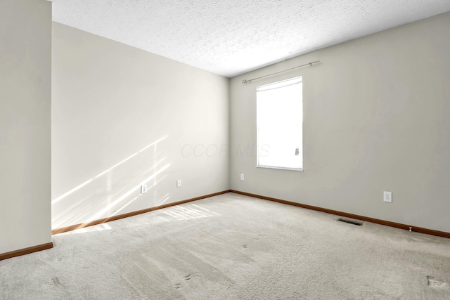 carpeted empty room with visible vents, baseboards, and a textured ceiling