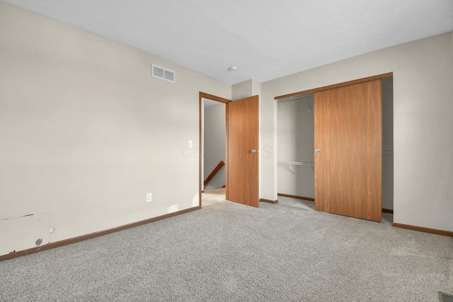 unfurnished bedroom featuring visible vents, baseboards, carpet floors, a closet, and a textured ceiling