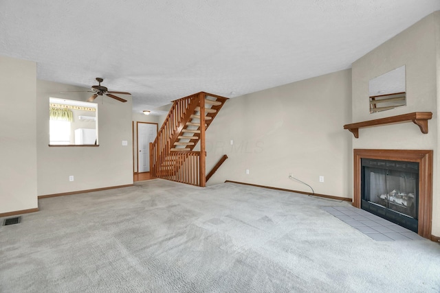 unfurnished living room featuring visible vents, baseboards, a fireplace with flush hearth, carpet flooring, and a textured ceiling