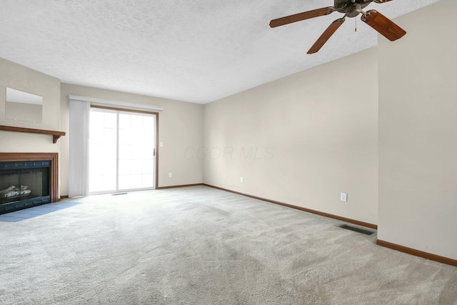 unfurnished living room with visible vents, baseboards, a fireplace with flush hearth, carpet flooring, and a textured ceiling