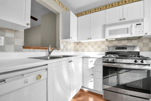 kitchen with a sink, tasteful backsplash, white cabinetry, white appliances, and light countertops