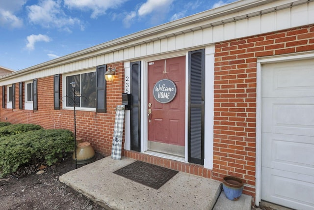 doorway to property with a garage and brick siding