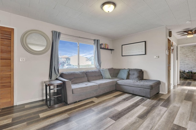 living area featuring ceiling fan, baseboards, and wood finished floors